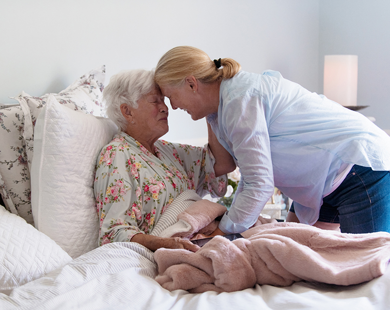 Elderly lady being offered supportive comfort care by caregiver at Oakdale assisted living facility