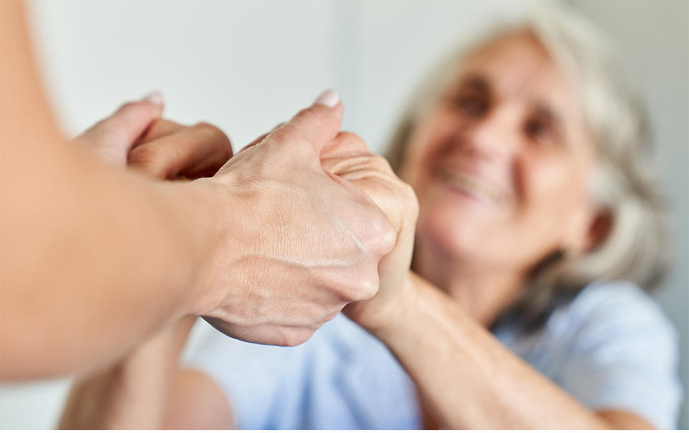 Caregiver holding hands with elderly lady