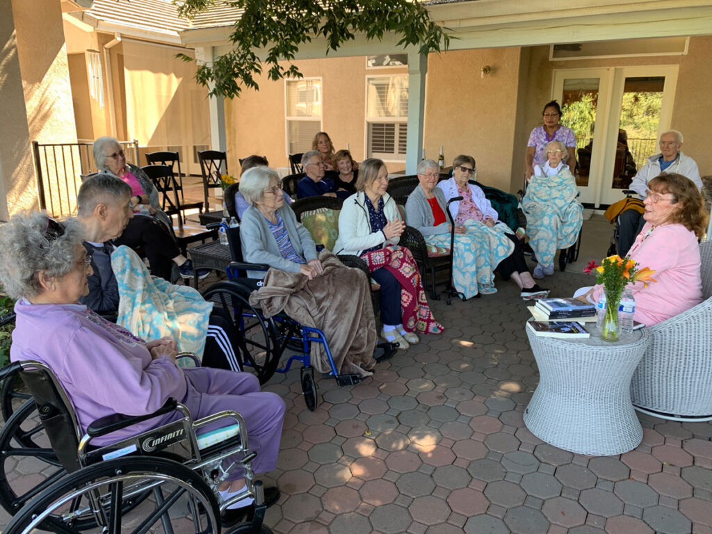 residents at Graceful Living in Modesto participate in a book club meeting listening to an author.